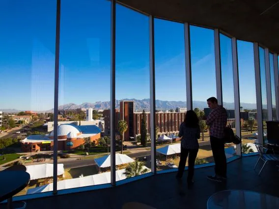 two people looking out a large window at our beautiful campus